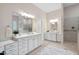 Elegant bathroom featuring double vanity, soaking tub, walk-in shower with glass blocks and neutral tile at 209 Bailey Ridge Dr, Morrisville, NC 27560