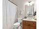 Well-lit bathroom with a white patterned shower curtain, light wood cabinets, and neutral paint at 209 Bailey Ridge Dr, Morrisville, NC 27560