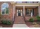 Charming front porch with brick steps, columns, and a black front door at 209 Bailey Ridge Dr, Morrisville, NC 27560