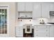 Kitchen boasts white cabinetry, quartz countertops, and built-in desk area with natural light from large window at 209 Bailey Ridge Dr, Morrisville, NC 27560