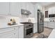 Kitchen features stainless steel oven, range hood, and refrigerator complemented by white cabinets and subway tile backsplash at 209 Bailey Ridge Dr, Morrisville, NC 27560