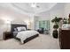 Tranquil main bedroom featuring tray ceilings and large windows with views of the outdoors at 209 Bailey Ridge Dr, Morrisville, NC 27560