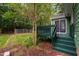 Green-painted deck steps down to a mulched area with trees and greenery in the backyard at 2724 Glastonbury Rd, Apex, NC 27539