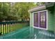 View of the green wooden deck and purple framed glass doors surrounded by lush trees at 2724 Glastonbury Rd, Apex, NC 27539