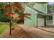View of a green home's garage with a concrete driveway and adjacent Japanese Maple at 2724 Glastonbury Rd, Apex, NC 27539