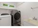Well-lit laundry room with modern washer, dryer, sink and wire shelving at 2724 Glastonbury Rd, Apex, NC 27539