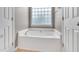 Clean bathroom featuring a soaking tub with glass block window for natural light and privacy at 3027 Courtney Creek Blvd, Durham, NC 27713