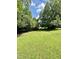 Expansive grassy area surrounded by mature trees with blue sky at 304 Sandalwood Ave, Louisburg, NC 27549