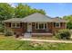 Charming brick home featuring a cozy front porch, complemented by a well-maintained lawn and mature trees at 305 Oakgrove Dr, Graham, NC 27253
