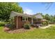 Well-kept brick home showcasing manicured landscaping and a cozy front porch with attractive black railings at 305 Oakgrove Dr, Graham, NC 27253