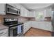 Kitchen equipped with stainless steel appliances, white cabinets, and tile backsplash, offers both style and functionality at 305 Oakgrove Dr, Graham, NC 27253