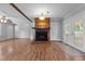 Bright living room featuring a brick fireplace, wood-look flooring, and a door to the outdoor area at 305 Oakgrove Dr, Graham, NC 27253