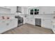 Well-lit kitchen boasting white cabinets, stainless steel appliances, and durable wood-look flooring at 305 W Canary St, Dunn, NC 28334