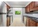 Galley kitchen with wood cabinetry, stainless steel appliances, and view into living area at 3088 Colony Rd # A, Durham, NC 27705