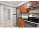 Compact kitchen equipped with stainless steel appliances, wooden cabinets, and tile backsplash at 3088 Colony Rd # A, Durham, NC 27705