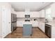 Well-lit kitchen with white cabinets, stainless steel appliances, a gray island, and hardwood flooring at 31 Pascoli Ct, Clayton, NC 27527