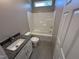 Bathroom with a white tub and shower, toilet, and a vanity with a gray granite countertop at 311 W Market St, Graham, NC 27253