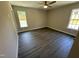 A bedroom featuring gray wood-look flooring, a ceiling fan, neutral paint, and two windows at 311 W Market St, Graham, NC 27253