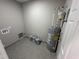 Clean utility room with a water heater, plumbing connections, and ceramic tile floors at 311 W Market St, Graham, NC 27253