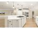 Open concept kitchen island featuring gas cooktop, white cabinets, stone countertops, stainless appliances and hardwood floors at 3124 Briar Stream Run, Raleigh, NC 27612