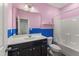 Bathroom featuring pink walls, black vanity, a large mirror, and a shower-tub combo at 409 Rhamkatte Rd, Holly Springs, NC 27540