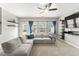 A bright living room features a gray sectional sofa, large windows, and a modern ceiling fan at 409 Rhamkatte Rd, Holly Springs, NC 27540