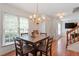 Inviting dining room with a chandelier, wood floors, and bright natural light streaming through the windows at 4108 Lazyriver Ln, Durham, NC 27712