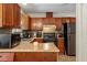 Well-lit kitchen features wooden cabinetry, backsplash, countertops and a black fridge at 4108 Lazyriver Ln, Durham, NC 27712