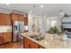 Granite countertop island and wood cabinets in an open kitchen with stainless steel appliances and a view of a living area at 4120 Overcup Oak Ln, Cary, NC 27519