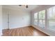 Bright bedroom featuring hardwood floors, a ceiling fan, three windows, and light-colored walls at 421 Old Ride Dr, Holly Springs, NC 27540