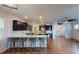 Open-concept kitchen with dark cabinets, island seating, stainless appliances, and hardwood flooring throughout the living space at 421 Old Ride Dr, Holly Springs, NC 27540
