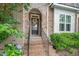 Inviting front entrance features stone archway, brick steps, wrought iron railing and decorative front door with wreath at 43 Salt Cedar Ln, Chapel Hill, NC 27516