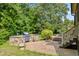 Backyard with a stone outdoor kitchen, hot tub, and surrounding greenery at 4720 Yates Mill Pond Rd, Raleigh, NC 27606