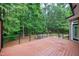 An angled view shows a back deck with a metal railing with a seating area nestled among the trees at 4924 Stoneyoak Ln, Raleigh, NC 27610