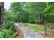 An eye-level view shows the lush landscaping, stone path, seating, and a peek at the back deck at 4924 Stoneyoak Ln, Raleigh, NC 27610