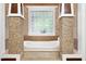 Luxurious bathroom with a soaking tub, stone columns, and a window letting in plenty of natural light at 4924 Stoneyoak Ln, Raleigh, NC 27610
