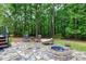 Charming patio area with stone flooring, a cozy fire pit, and comfortable seating amidst a wooded backyard at 4924 Stoneyoak Ln, Raleigh, NC 27610