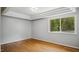 A sunny bedroom features hardwood floors, gray walls, and ample natural light from a large window at 5820 Wake Forest Hwy, Durham, NC 27703