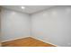 A minimalist bedroom with hardwood floors, light gray walls, and essential electrical outlets at 5820 Wake Forest Hwy, Durham, NC 27703