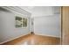 Sunlit bedroom boasts hardwood floors, gray walls, and a view to the backyard at 5820 Wake Forest Hwy, Durham, NC 27703