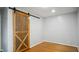 A serene bedroom space featuring hardwood floors, light walls, and a rustic sliding door at 5820 Wake Forest Hwy, Durham, NC 27703