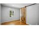 A calming bedroom with hardwood floors, light gray walls, and a unique sliding wooden door at 5820 Wake Forest Hwy, Durham, NC 27703