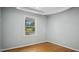 A simple bedroom with hardwood floors, light gray walls, and natural light from a window at 5820 Wake Forest Hwy, Durham, NC 27703