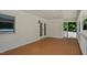 Spacious covered patio with a stained wood floor, white brick wall, and enclosed side with views of trees at 5820 Wake Forest Hwy, Durham, NC 27703