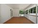 Spacious covered patio with a stained wood floor, white brick wall, and enclosed side with views of trees at 5820 Wake Forest Hwy, Durham, NC 27703
