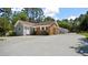 Charming single-story home featuring a brick facade, white trim, and an expansive driveway surrounded by mature trees at 5820 Wake Forest Hwy, Durham, NC 27703
