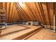 Unfinished attic space featuring exposed rafters, plywood flooring, storage shelving, and some stored household items at 6005 Carlyle Dr, Raleigh, NC 27614