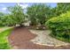 Backyard stone patio with mature trees and lush landscaping, providing a private seating area at 6005 Carlyle Dr, Raleigh, NC 27614