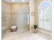 Bathroom shower featuring neutral tile and glass door, plus a window with shutters at 6005 Carlyle Dr, Raleigh, NC 27614