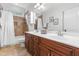 Well-lit bathroom features double sinks, cherry cabinets, and tiled shower-tub combo with linen storage at 6005 Carlyle Dr, Raleigh, NC 27614